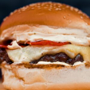 Close-up of a delicious cheeseburger with fresh toppings on a wooden board.