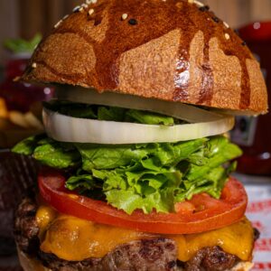 Mouth-watering gourmet cheeseburger with fresh lettuce, tomato, and onion rings.