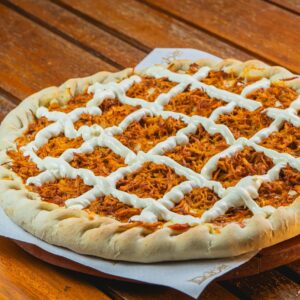 Savory barbecue chicken pizza topped with creamy sauce on a rustic wooden table.